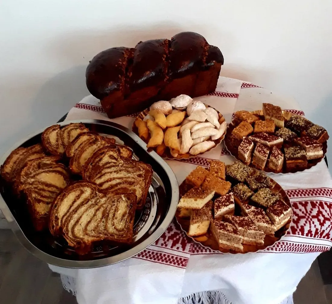 Cozonac întreg, felii de cozonac cu nucă și prăjituri de casă, așezate pe ștergar tradițional