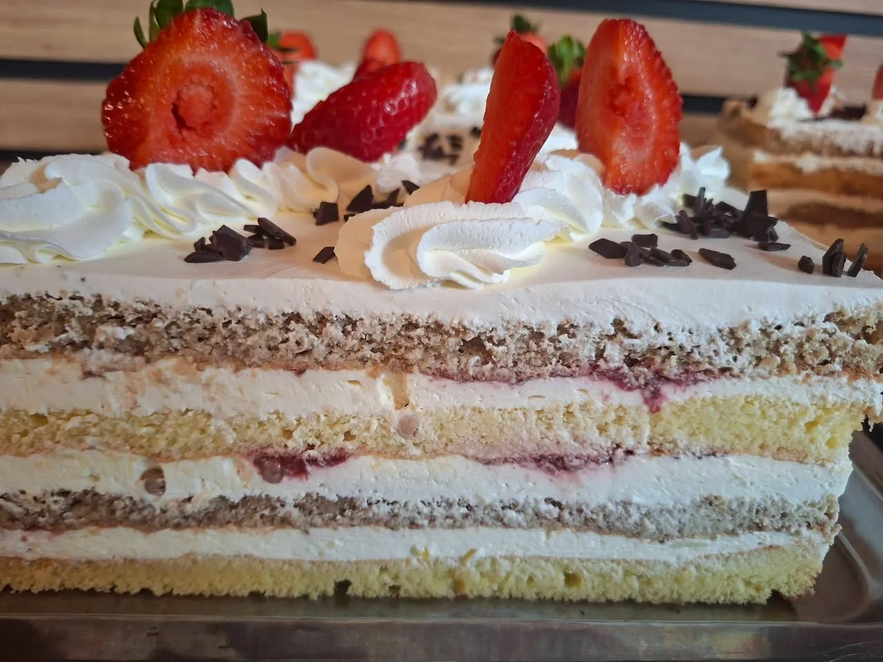 Felie de tort cu frișcă, blat de nucă și căpșuni proaspete