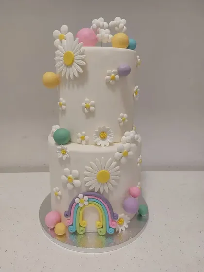 Tort etajat în culori pastel, cu curcubeu și margarete